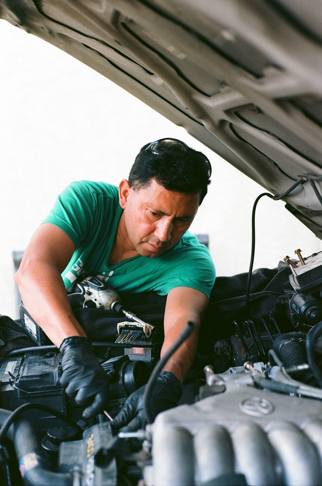 A man working under the hood of a vehicle