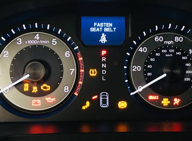 Nissan instrument cluster with lights on at auto repair shop.
